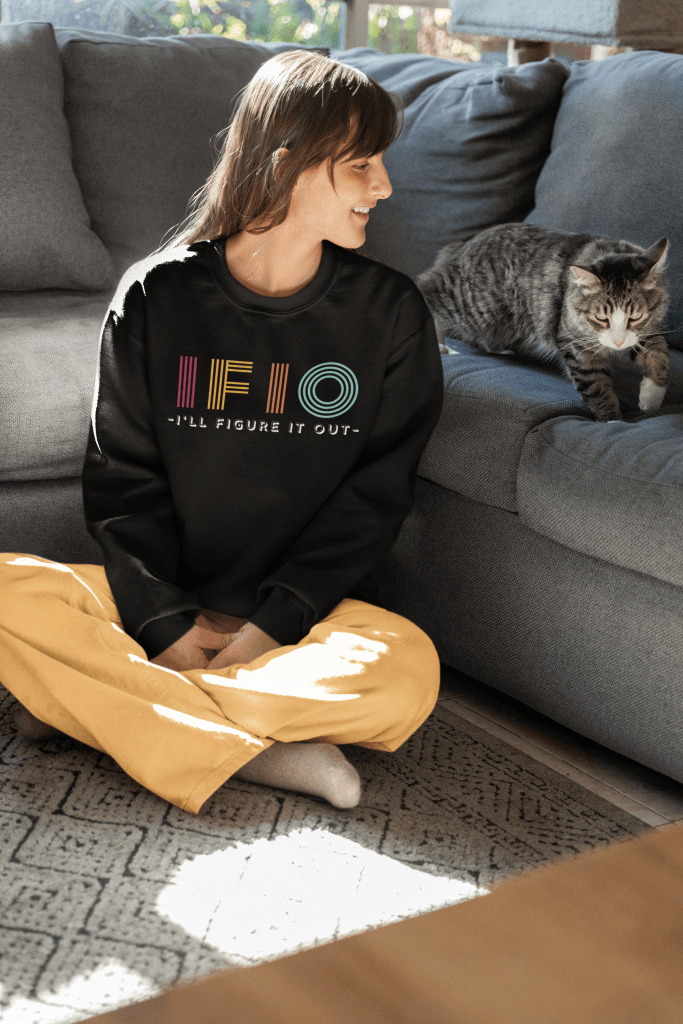 woman sitting on floor next to her cat. The woman is wearing and IFIO I'll Figure It Out black Sweatshirt