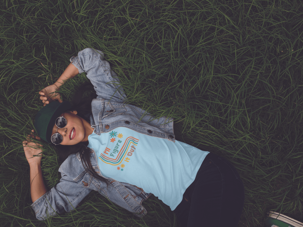 girl laying in the grass with a denim jean jacket wearing a blue retro wavy lines and flowers I'll Figure It Out t shirt